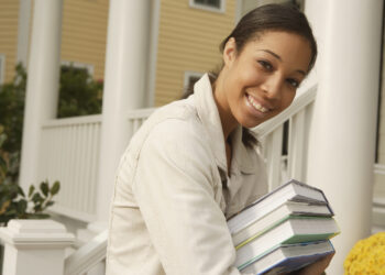 African woman carrying stack of books