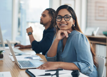 Portrait of a young businesswoman working in an office with her colleague in the background