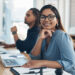 Portrait of a young businesswoman working in an office with her colleague in the background